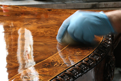 Instructor wearing gloves French polishing a wooden table